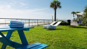Un espace extérieur verdoyant avec une table de billard, des chaises longues et une vue sur la plage.