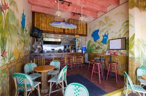 A restaurant interior with bamboo walls, green and red bar stools, and a central bar area. - Spectacular New King Studio w/kitchenette, pool (Daytona Beach)