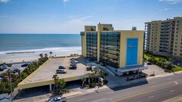 Un hotel con estacionamiento, vistas a la playa y un edificio grande con puerta azul.