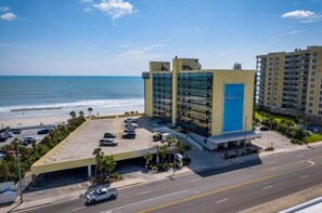Hotel amb pàrquing, vistes a la platja i un edifici gran amb una porta blava.