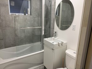 Ein Badezimmer mit einer Duschkabine, einem weißen Waschbecken und einer Toilette.
