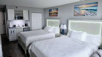 Habitación de hotel con dos camas, kitchenette y obras de arte en las paredes.