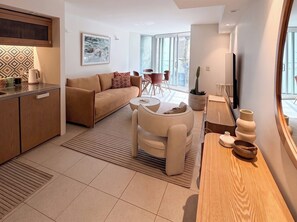 A modern living room with a sofa, a coffee table, and a dining area with chairs. - Luxury Studio Bondi Beach Front (Bondi Beach)