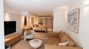 Une chambre d’hôtel moderne avec un lit, un canapé, une télévision et un tableau au mur.