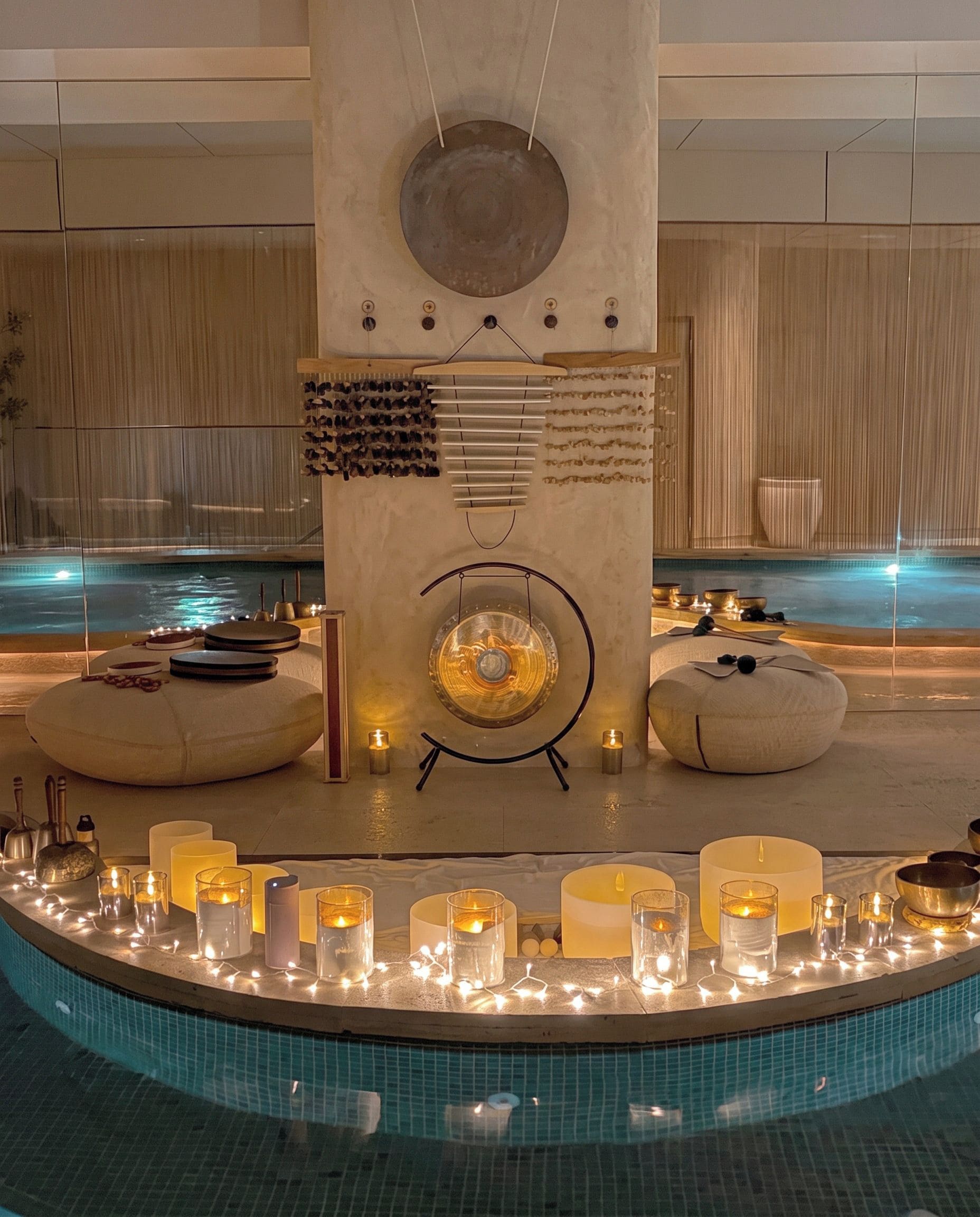 A modern spa area with a pool, candles, and relaxation furniture.