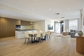 A modern apartment with a dining area, kitchen, and living space. - Starboard Cove (Safety Beach)