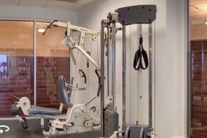 A gym with exercise equipment, including a cable machine and a bench. - Spacious 1bdrm direct oceanfront w/private balcony (Daytona Beach)