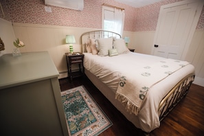 A bedroom with a bed, bedside table, lamp, and a small vase with a flower. - Garden Gate Farmhouse- a peaceful retreat with hot tub and hammocks! (Skaneateles)