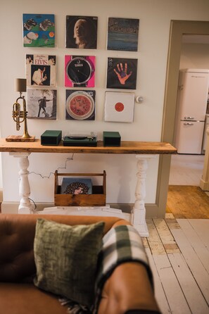 Ein Zimmer mit einem Holztisch, auf dem Schallplatten, eine Blechtrompete und ein altes Radio ausgestellt sind.