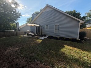 A residential house with a covered patio, a fenced yard, and a small garden area. - ATL Hideaway....2-bedroom house in tranquil Atlanta perfect for a relaxing stay (Atlanta)