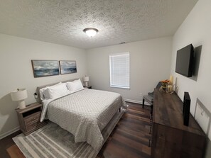 A bedroom with a bed, nightstands, a dresser, a TV, and a window with blinds. - ATL Hideaway....2-bedroom house in tranquil Atlanta perfect for a relaxing stay (Atlanta)