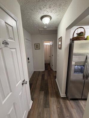 A hallway with a refrigerator on the right, a door with a 'NO GUEST ACCESS' sign on the left, and a ceiling light. - ATL Hideaway....2-bedroom house in tranquil Atlanta perfect for a relaxing stay (Atlanta)