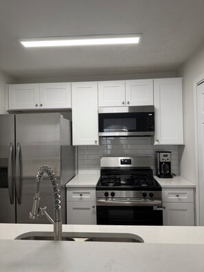 A modern kitchen with white cabinets, stainless steel appliances, and a built-in oven. - ATL Hideaway....2-bedroom house in tranquil Atlanta perfect for a relaxing stay (Atlanta)