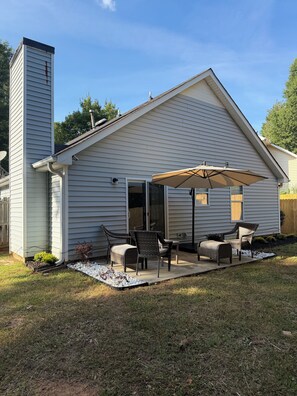 A house with a covered patio area featuring outdoor furniture and a large umbrella. - ATL Hideaway....2-bedroom house in tranquil Atlanta perfect for a relaxing stay (Atlanta)