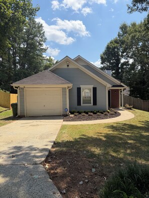 A single-story house with a garage, a front yard with a lawn, and a wooden fence. - ATL Hideaway....2-bedroom house in tranquil Atlanta perfect for a relaxing stay (Atlanta)