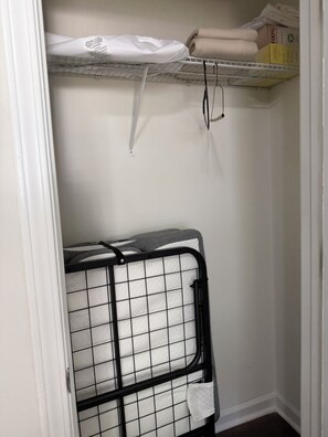 A storage area with a metal rack holding folded towels and a white shelf with boxes. - ATL Hideaway....2-bedroom house in tranquil Atlanta perfect for a relaxing stay (Atlanta)