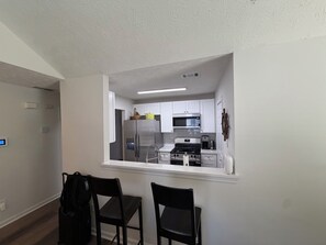 A modern kitchen with white cabinets, stainless steel appliances, and a window overlooking the dining area. - ATL Hideaway....2-bedroom house in tranquil Atlanta perfect for a relaxing stay (Atlanta)