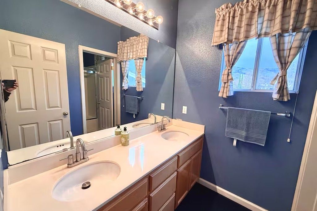 A bathroom with two sinks, a large mirror, and a towel rack.