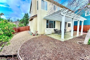 A covered patio area with a pergola, a table and chairs, and a garden bed with mulch. - 3310 Tremendous 3-bedroom house with AC in San Jose (San Jose)