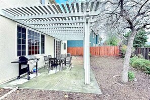An outdoor patio with a grill, table, and chairs.