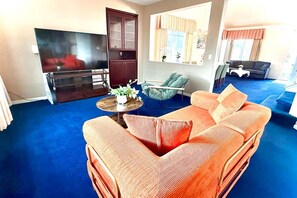 A living room with a sofa, a television, a cabinet, and a window with curtains.