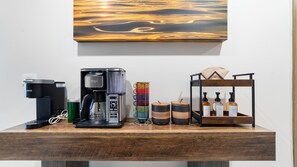A wooden coffee station with a coffee maker, a mug, a glass, and a shelf with bottles. - One 503B Studio: Vista del Sol Studio (Puerto Peñasco)