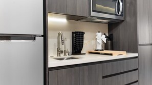 A modern kitchen with a built-in microwave, stainless steel sink, and a black towel rack. - One 503B Studio: Vista del Sol Studio (Puerto Peñasco)