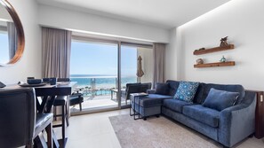 A modern living room with a large window, a sofa, a dining area, and a view of the beach. - One 503B Studio: Vista del Sol Studio (Puerto Peñasco)
