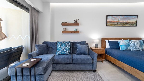 Ein modernes Schlafzimmer mit einer Couch, einem Bett, einem Nachttisch und einem Wandregal.