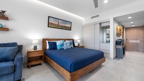 Ein modernes Schlafzimmer mit einem großen Bett, Nachttischen, einem Sessel, einem Gemälde und einem Kleiderschrank.