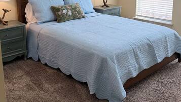 A bedroom with a bed, two bedside tables, a ceiling fan, and a window with blinds.