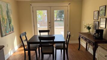 A dining area with a table and chairs, a coffee maker, and a painting on the wall.