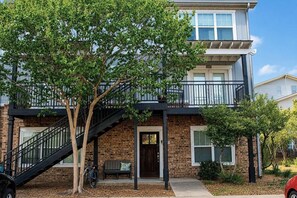 A two-story building with a brick facade, a balcony on the upper floor, and a staircase leading to the entrance.