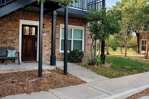 A brick building with a dark brown door, a bench outside, and a number '517' on the wall.