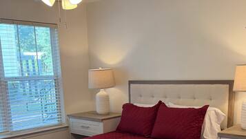 A bedroom with a bed, nightstands, a ceiling fan, and a window with blinds.