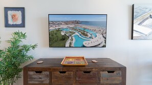 A framed photograph of a resort with a pool and beach, a wooden cabinet with drawers, and a plant. - Two 803A  Hotel Room - Sea Breeze Suite (Puerto Peñasco)