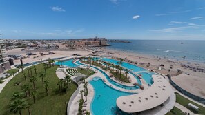 Ein Resort mit mehreren Schwimmbecken, einem Strand und Blick auf den Ozean.