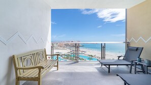A balcony with a wooden bench, a lounge chair, and a table with a glass top. - Two 803A  Hotel Room - Sea Breeze Suite (Puerto Peñasco)