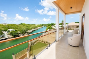A balcony with a view of a river, a sandy beach, and greenery. - Villa Camila is a stylish, modern one-bedroom apartment, centrally located. (Providenciales)