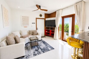 En moderne stue med sofa, sofabord og et spiseområde med bar.