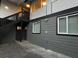 A two-story building with a staircase leading to an upper level, large windows with blinds, and a visible door.
