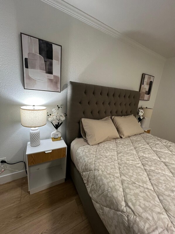 Un dormitorio con cama, mesita de noche, lámpara y decoración en la pared.