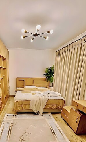 A bedroom with a bed, a ceiling light fixture, a plant, and a wardrobe. - Luxury Stay in Sheikh Zayed (Sheikh Zayed City)