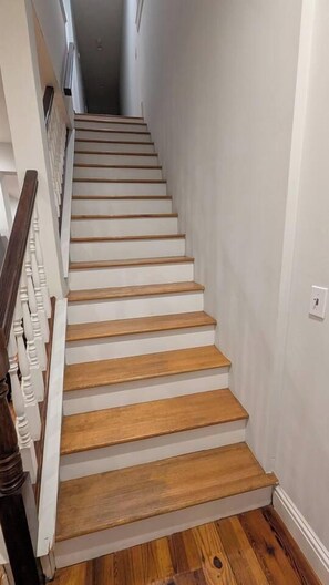 A staircase with wooden steps and white walls. - NEW! Benton Park Gem, Sleeps 8 & Dog Friendly - Stay Smiley Rentals (St. Louis)