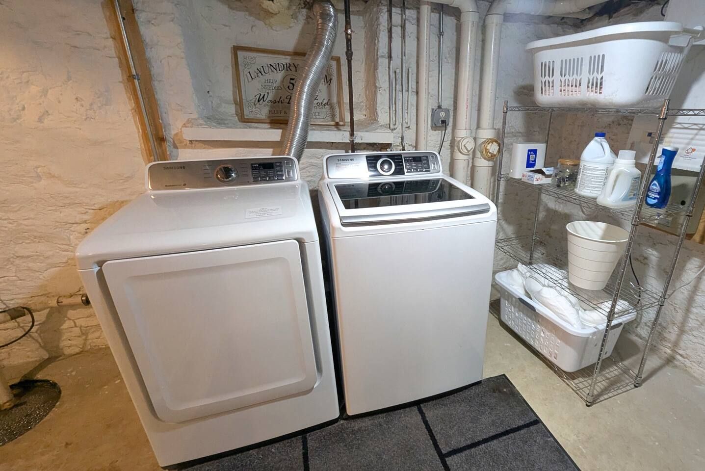 A laundry area with two washing machines and a shelf with cleaning supplies.