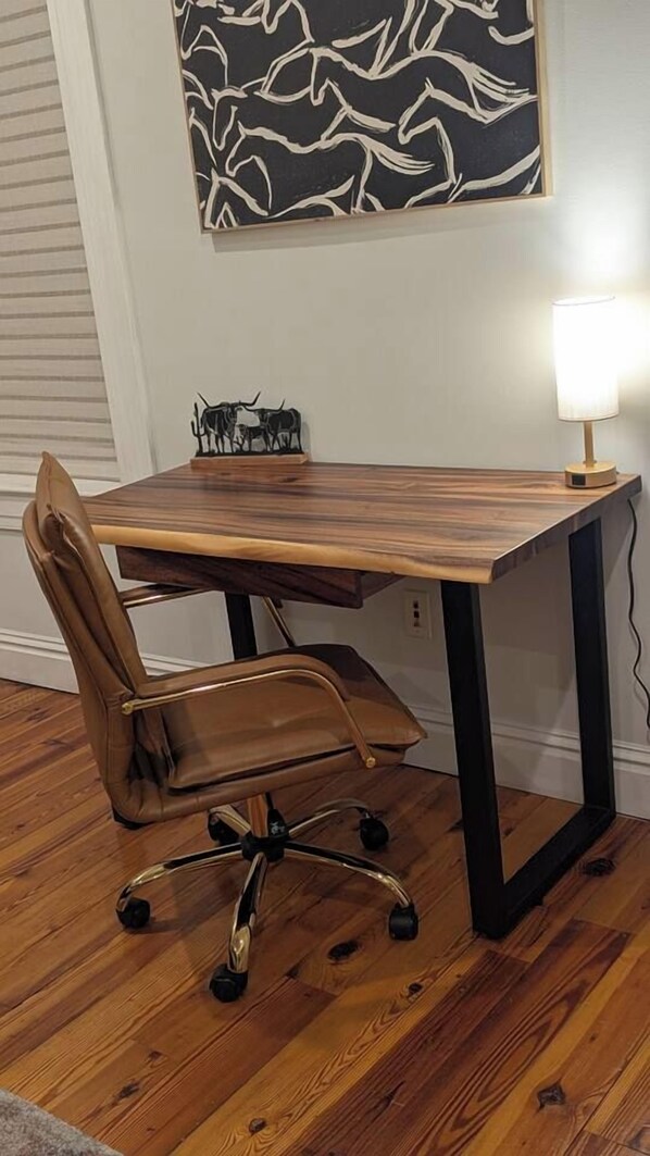 Un bureau en bois, une chaise, une lampe et une sculpture fixée au mur.