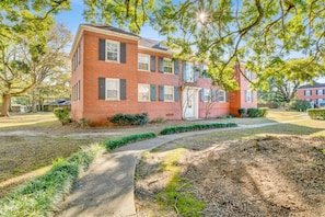 A brick building with a central door and windows, surrounded by a well-maintained lawn and trees. - Southern Comfort (Mobile)