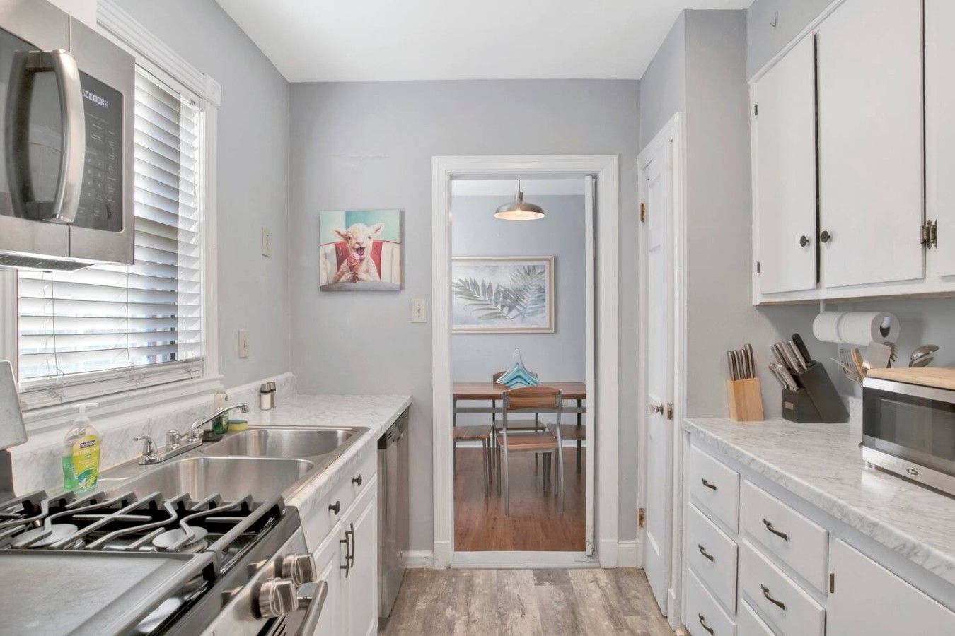 A modern kitchen with a gas stove, stainless steel appliances, and a dining area with a table and chairs.