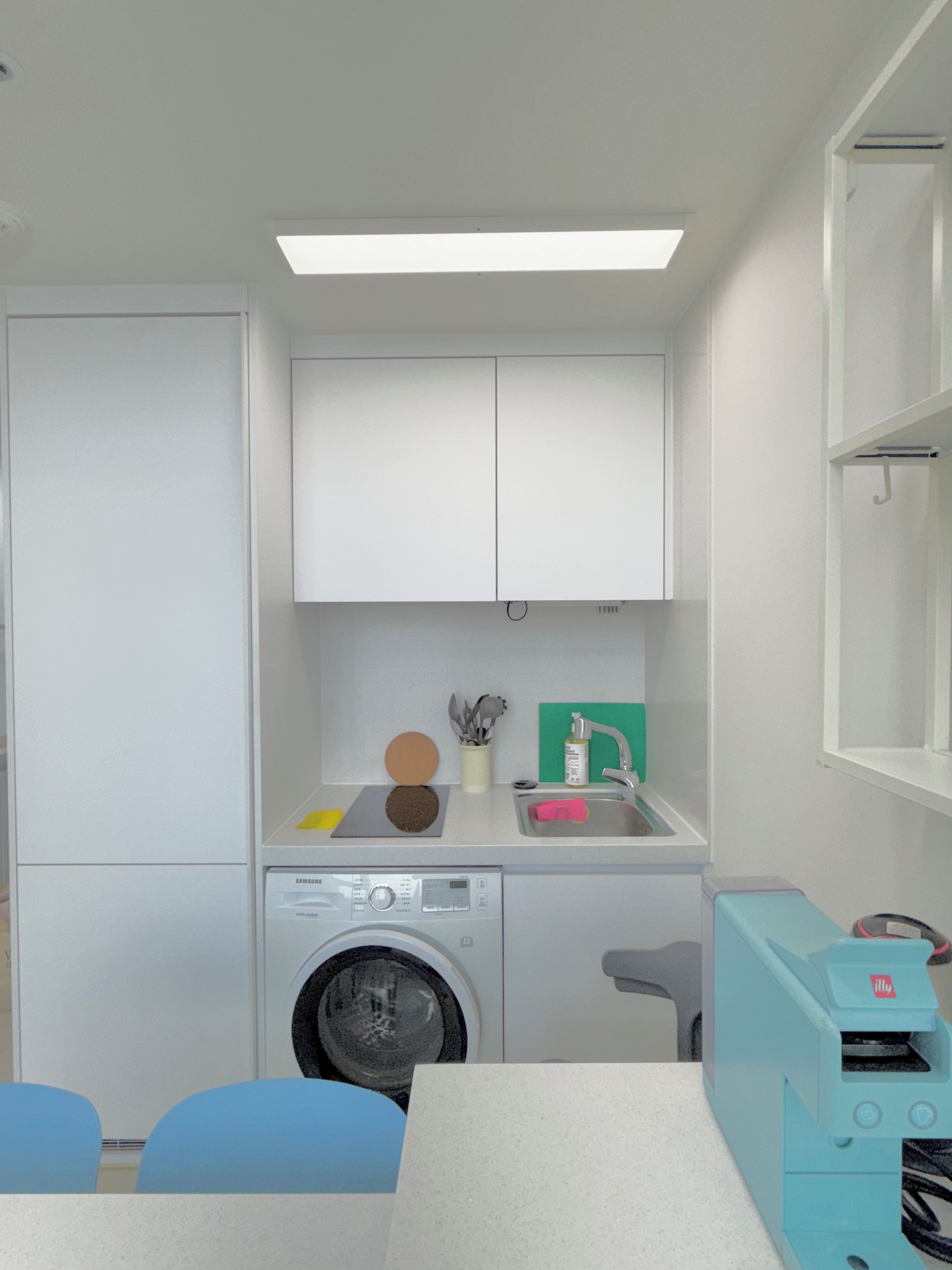 A compact kitchen with a washing machine, a sink, and a table with chairs.