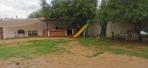A backyard with a barbecue area, a slide, and a brick wall.